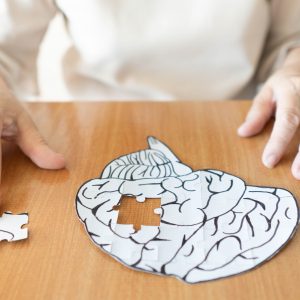 Elderly woman hands putting missing white jigsaw puzzle piece do